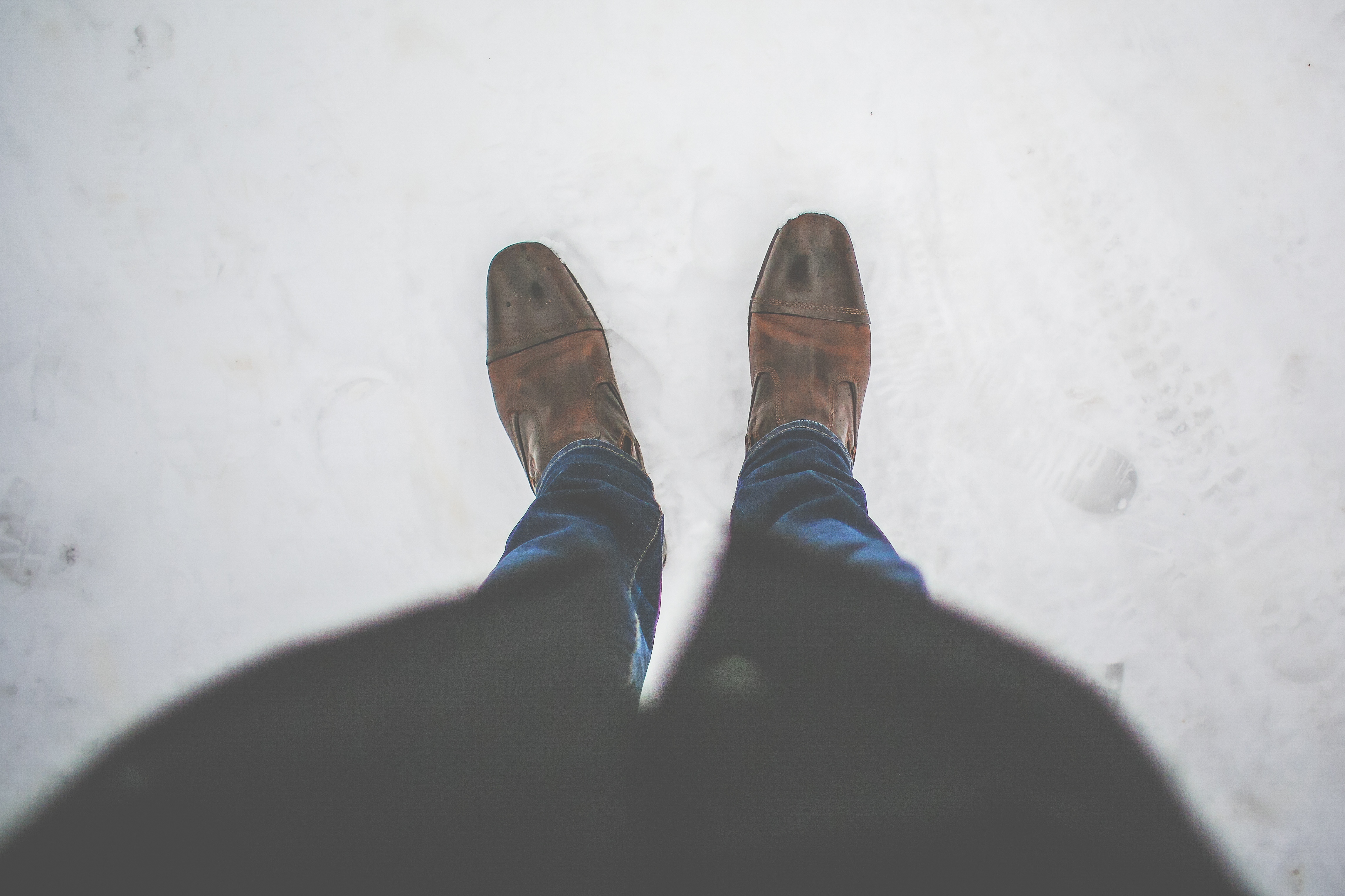 Man in leather boots standing in snow.  Bird's eye prospective of bottom half.